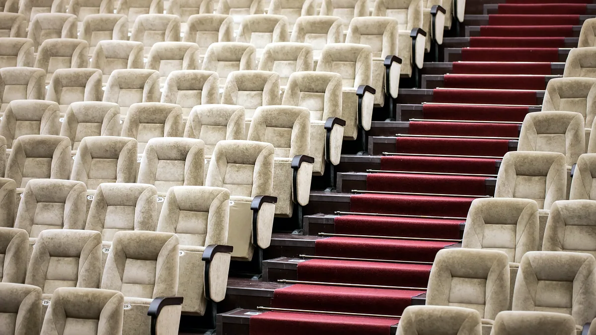 Rows of empty seats in a dim concert hall with the doors closed.