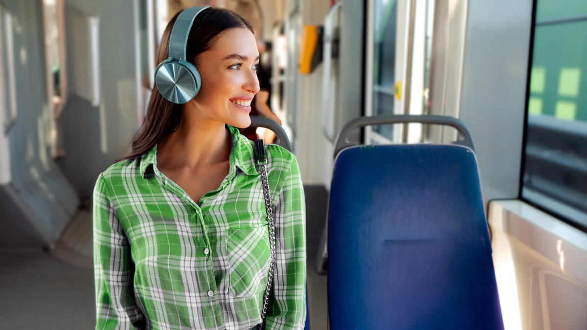 A commuter in headphones gazing out a train window.