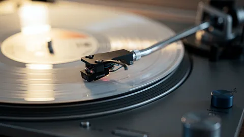 Illustration: A vinyl record on a spinning turntable with the tonearm lowered.