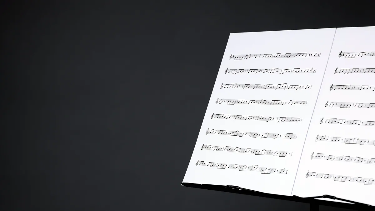 Orchestral sheet music fanned out on a black music stand.